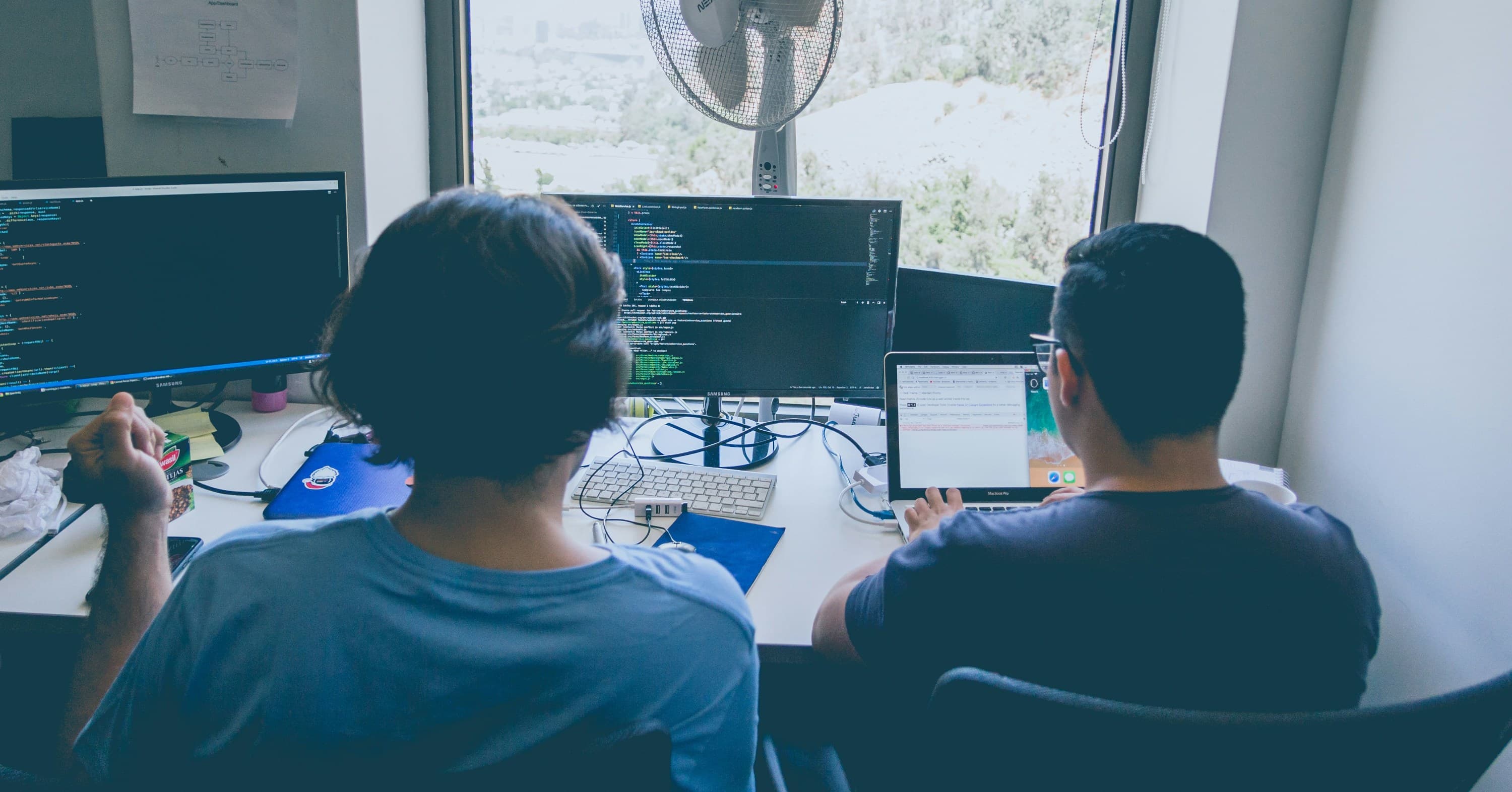 two men using computer and laptop